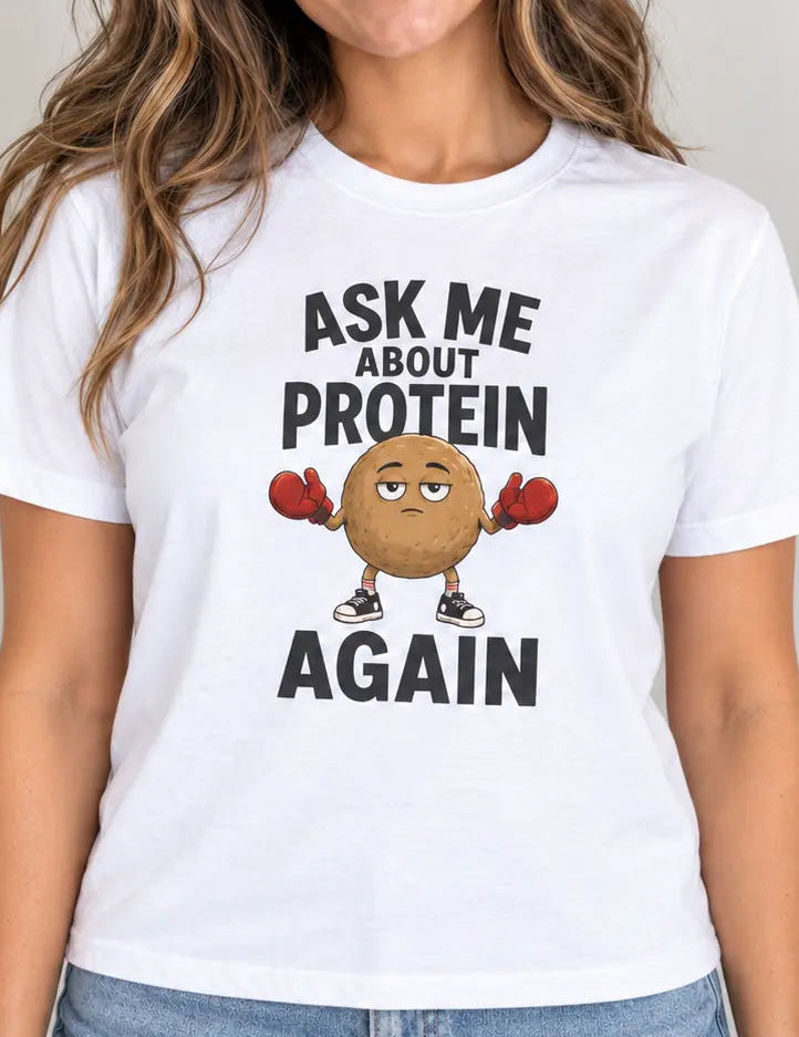 woman wearing a White t-shirt with cartoon graphic and text 'ask me about protein again'
