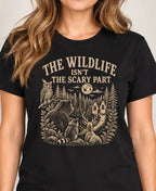 woman wearing a Black t-shirt with nature graphic of animals and halloween characters walking up a path and text 'the wildlife isn;t the scary part