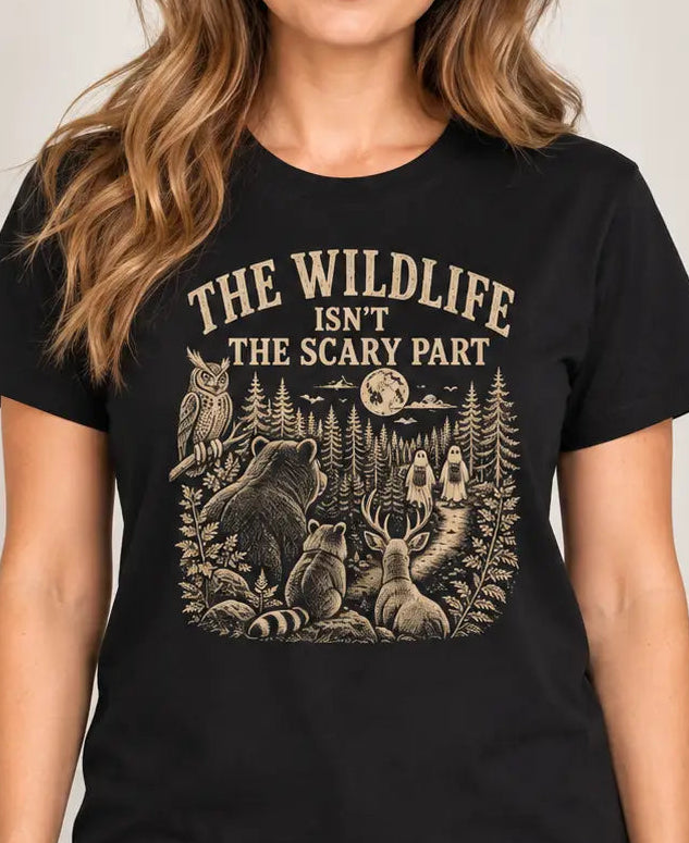 woman wearing a Black t-shirt with nature graphic of animals and halloween characters walking up a path and text 'the wildlife isn;t the scary part