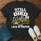 black t=shirt with a skeleton graphic and text 'still haven't dies from lack of protein'