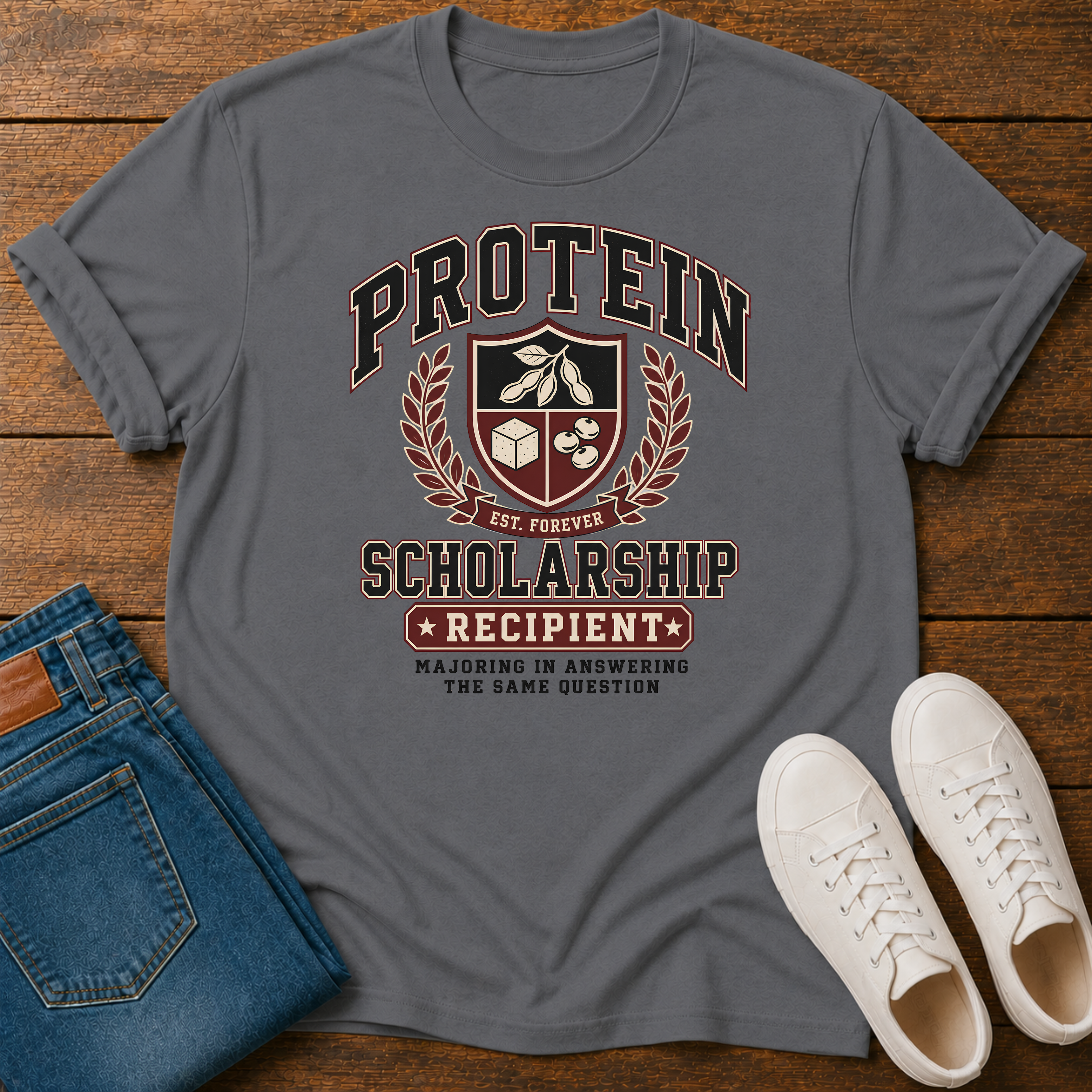 Charcoal T-shirt with Vintage collegiate crest design reading “Protein Scholarship Recipient” with soybean, tofu, and bean illustrations and the words “Majoring in Answering the Same Question.”