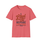 A coral pink short-sleeve crewneck t-shirt with a retro-style graphic on the chest that reads 'I Liked It BEFORE I WAS TOLD TO' in brown and navy blue lettering, displayed on a clean white background.