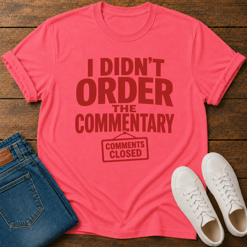 Pink t-shirt with humorous text on a wooden surface with jeans and shoes.