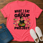 coral t-shirt with a graphic of a woman eating salad and non vegan questions being thrown at her with text 'what i eat is not a group project" on a wooden board with jeans and sneakers