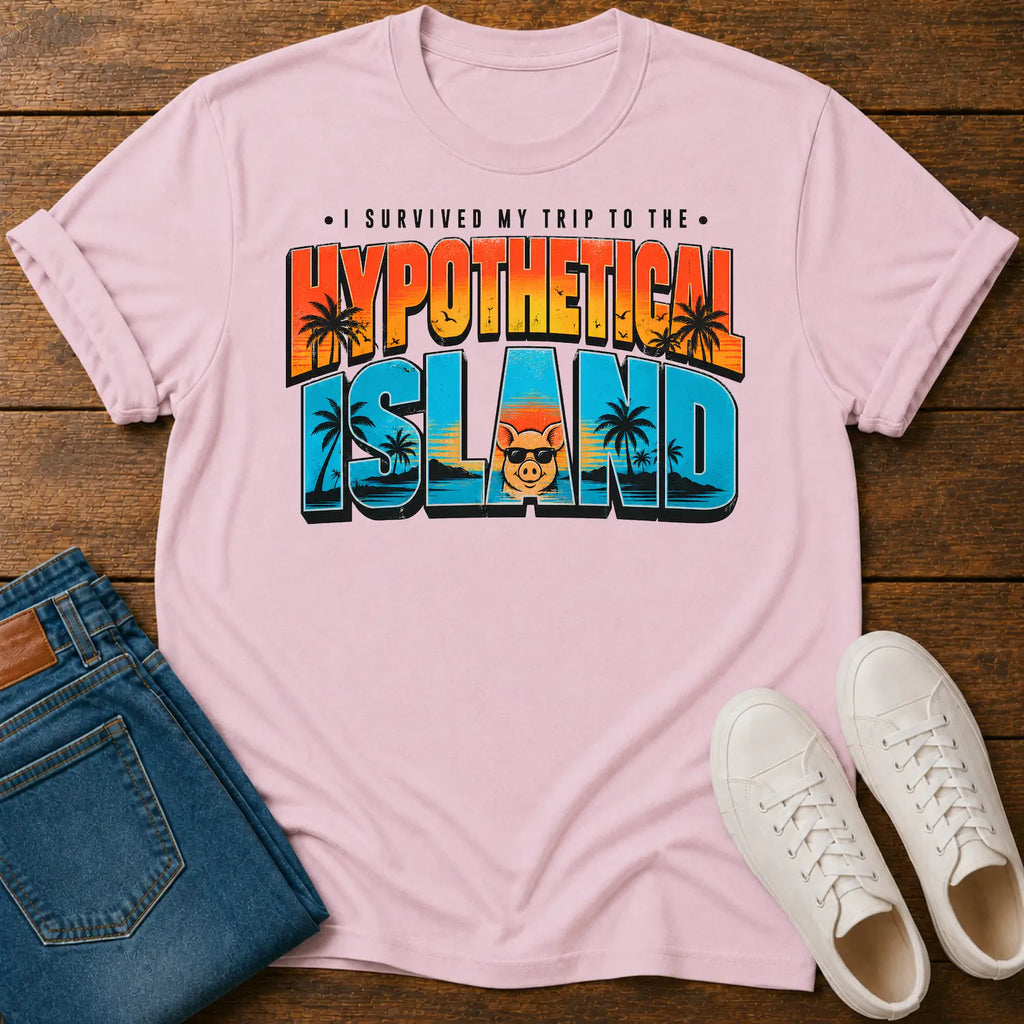 A light pink short-sleeve graphic T-shirt laid flat on a wooden surface, styled with folded blue jeans and white sneakers. The shirt has a large retro-style text graphic reading “I SURVIVED MY TRIP TO THE HYPOTHETICAL ISLAND” with palm trees and a cartoon face inside the lettering.