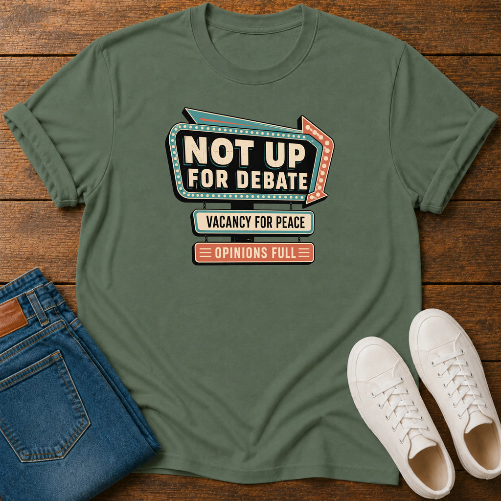 An olive green graphic t-shirt laid flat on a wooden surface, styled with folded blue jeans and white sneakers. The t-shirt features a retro marquee-style graphic that reads 'NOT UP FOR DEBATE' with 'VACANCY FOR PEACE' and 'OPINIONS FULL' underneath.
