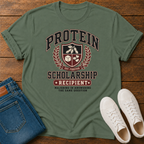 military green t-shirt with Vintage collegiate crest design reading “Protein Scholarship Recipient” with soybean, tofu, and bean illustrations and the words “Majoring in Answering the Same Question.”