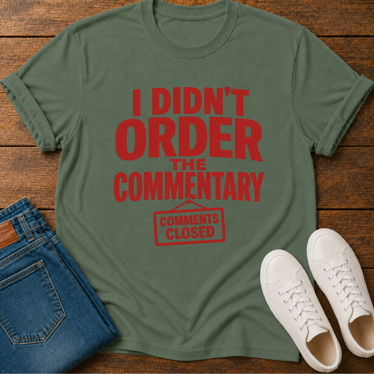 Green t-shirt with red text on a wooden surface with jeans and shoes.