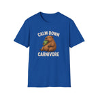 A royal blue short-sleeve crewneck t-shirt featuring a cartoon illustration of a brown groundhog eating green lettuce, with the text 'CALM DOWN CARNIVORE' printed in white above and below the graphic.