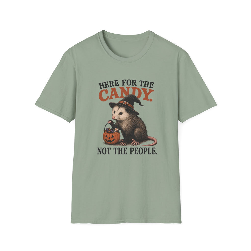 A sage green short-sleeve crewneck t-shirt featuring a Halloween graphic of an opossum in a witch hat holding a jack-o'-lantern, with the text 'HERE FOR THE CANDY. NOT THE PEOPLE.