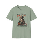 A sage green short-sleeve crewneck t-shirt featuring a Halloween graphic of an opossum in a witch hat holding a jack-o'-lantern, with the text 'HERE FOR THE CANDY. NOT THE PEOPLE.