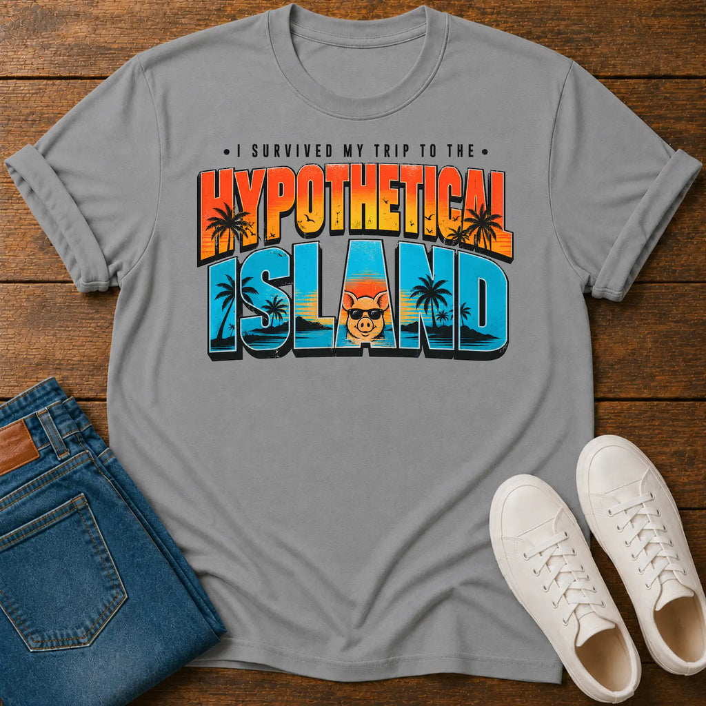 A light gray crewneck t-shirt with a colorful retro graphic reading 'I SURVIVED MY TRIP TO THE HYPOTHETICAL ISLAND' in orange, yellow, and blue gradient letters. The shirt is styled in a flat-lay on a dark wood background, accompanied by folded blue jeans and a pair of white sneakers.