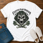 A white graphic t-shirt featuring a cartoon gorilla wearing sunglasses and holding a banana, surrounded by the text 'PROTEIN DEFICIENCY SURVIVOR' in brown and teal. The shirt is styled in a flat-lay arrangement on a dark wood background, accompanied by blue jeans and white sneakers.
