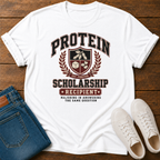 white t-shirt with Vintage collegiate crest design reading “Protein Scholarship Recipient” with soybean, tofu, and bean illustrations and the words “Majoring in Answering the Same Question.”