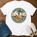 A white short-sleeve graphic T-shirt laid flat on a wooden surface, styled with folded blue jeans and white sneakers. The shirt features a large circular retro-style beach illustration with the text 'SURVIVED THE HYPOTHETICAL ISLAND' and a person sitting on a beach with a palm tree and coconut.