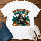 A white t-shirt with a gorilla graphic surrounded by leaves and nuts with text 'protein deficiency survivor.'