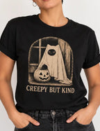 Woman wearing a black short sleeved t-shirt with halloween graphic and text'creepy but kind'